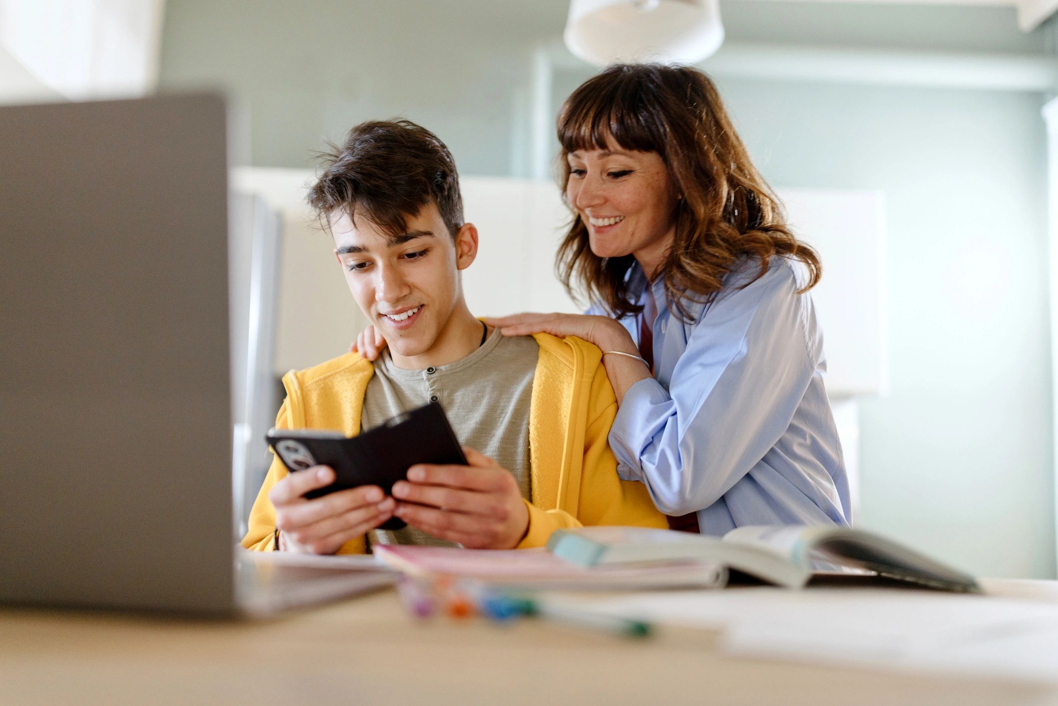 parent and teen studying together with digital device